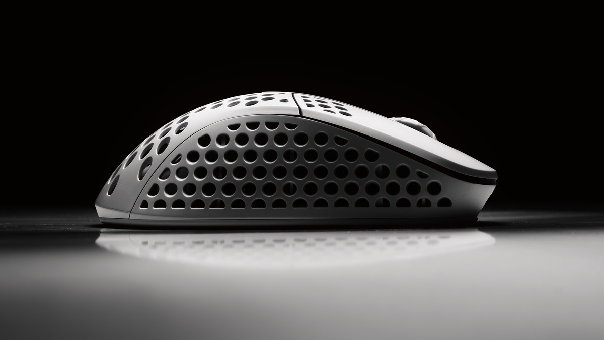White honeycomb-shell gaming mouse rim-lit on black with a mirror reflection