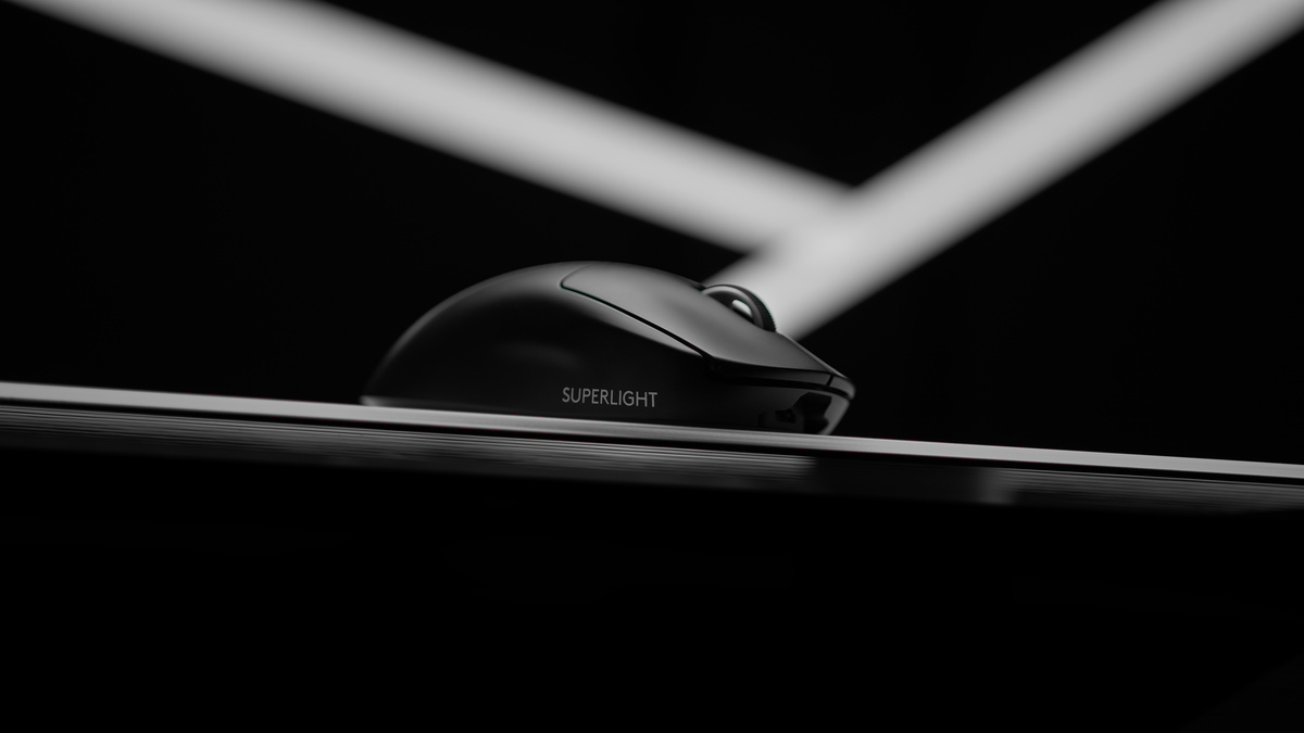 Black wireless gaming mouse on a dark surface under two crossed white light beams