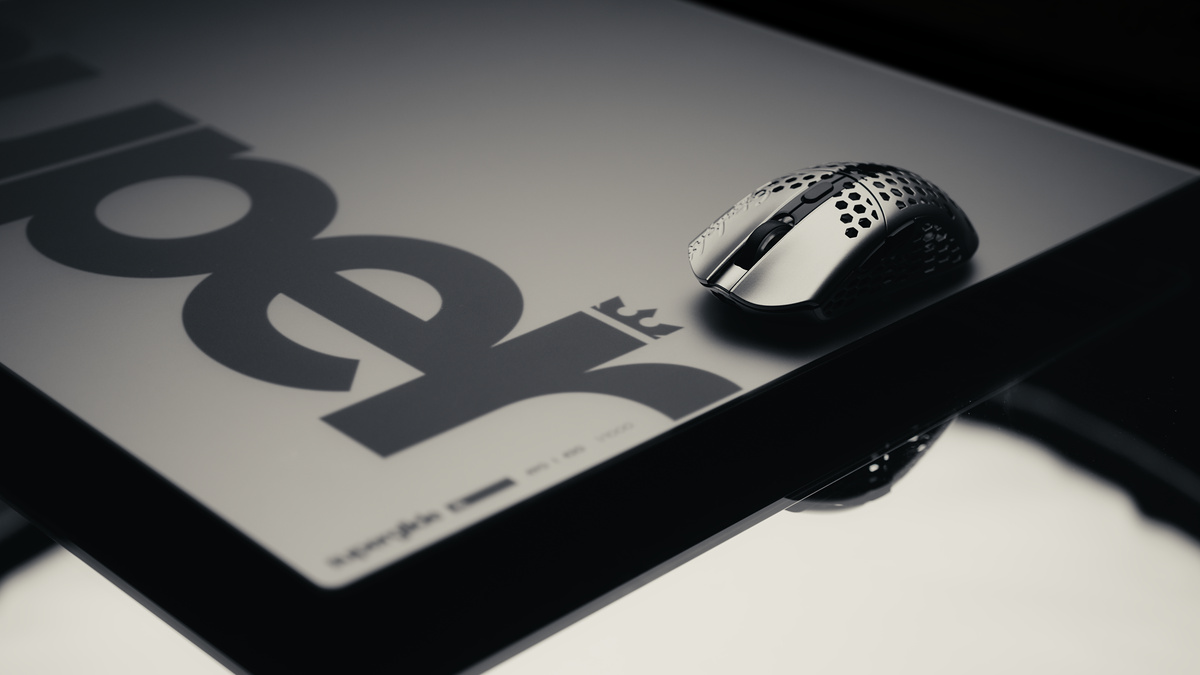 High-contrast monochrome shot of a honeycomb mouse on a mousepad printed with a large wordmark