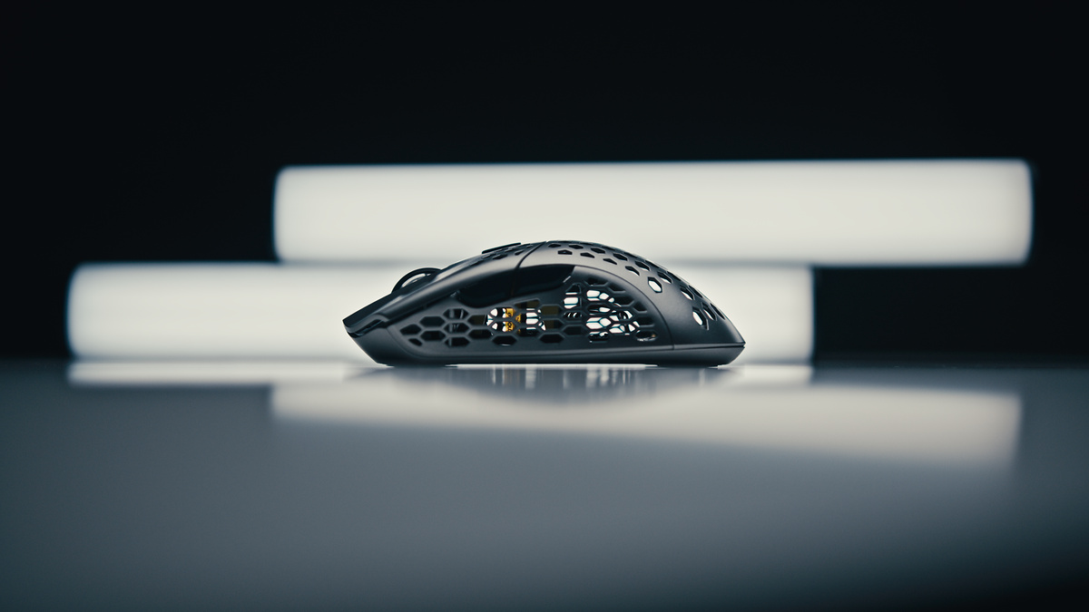 Low-angle profile of an open-frame gaming mouse between two horizontal light bars, reflected in a glossy surface